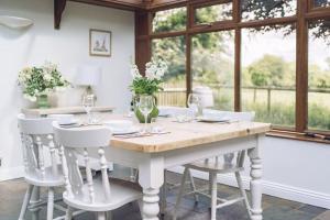 ein weißes Esszimmer mit einem Holztisch und weißen Stühlen in der Unterkunft Detached homely bungalow with open fireplace in Priors Marston