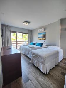 a hotel room with two beds and a window at Pousada Waikiki Boutique in Pipa