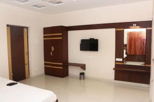 Pokój z łóżkiem i telewizorem na ścianie w obiekcie Elgozo Hotel Dreams Parasise w mieście Yercaud