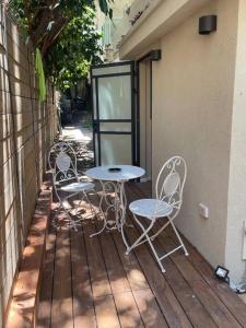 3 chaises et une table sur une terrasse en bois dans l'établissement דירת גן יפהפיה בחובבי ציון, à Tel Aviv