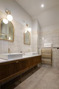 a bathroom with two sinks and two mirrors at Worplesdon Place Hotel in Guildford