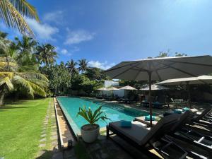 una piscina con tumbonas y sombrilla en Calamansi Cove Villas, en Balapitiya