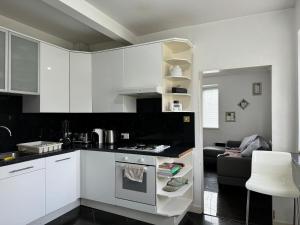 a kitchen with white cabinets and a stove top oven at Idyllic Cottage in Jubilee Park in London