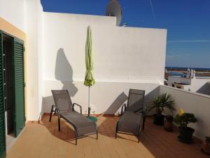 - une terrasse avec des chaises et un parasol dans un bâtiment dans l'établissement Apartamento Vista Mar, à Cabanas de Tavira