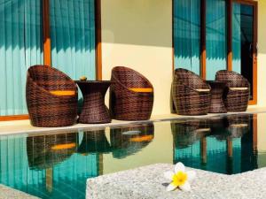 - un groupe de paniers en osier assis à côté d'une piscine dans l'établissement Utopia Resort, à Lamai