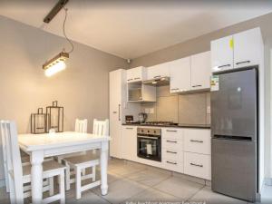 eine Küche mit weißen Schränken, einem Tisch und einem Kühlschrank in der Unterkunft Kelly's Beachfront Apartments in Port Alfred