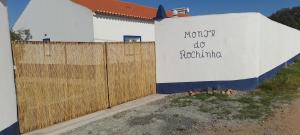 biały budynek z drewnianym płotem obok w obiekcie Monte do Rochinha w mieście Monte da Cardosa