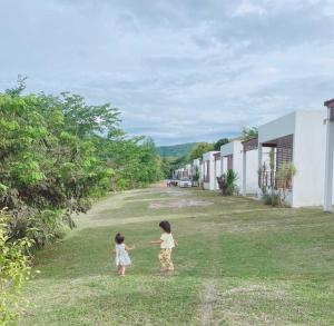 dos niñas están de pie en la hierba en โรงแรม ต้นสัก เลย รีสอร์ท Tonsak Loei Resort&Hotel en Wang Saphung