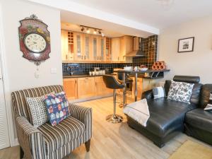 ein Wohnzimmer mit einer Couch und einer Uhr an der Wand in der Unterkunft Anchor Cottage in Weymouth