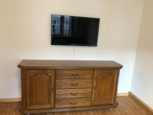 a wooden dresser with a television on a wall at Ferienwohnung Monteurzimmer Heinzberg Haus Arnstadt in Arnstadt