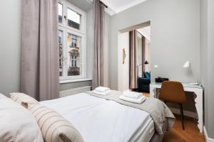 Biała sypialnia z łóżkiem, biurkiem i oknem w obiekcie Classy Old Town Suites w Krakowie