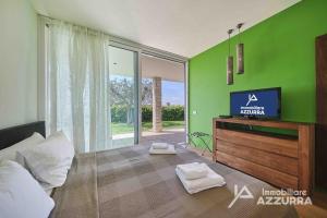 sala de estar con TV y pared verde en Villa Madabà - Immobiliare Azzurra, en Bardolino