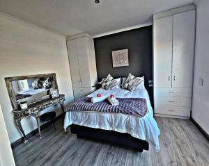 1 dormitorio con cama con espejo y escritorio en Feel@Home, en Ciudad del Cabo