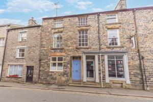 an old brick building with a blue door on a street at Tastefully decorated, family friendly property, central Kirkby Lonsdale, parking and EV charger in Kirkby Lonsdale