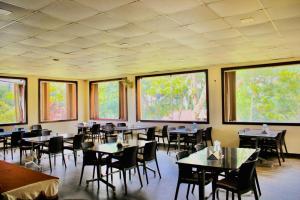 jadalnia ze stołami, krzesłami i oknami w obiekcie Elgozo Hotel Dreams Parasise w mieście Yercaud