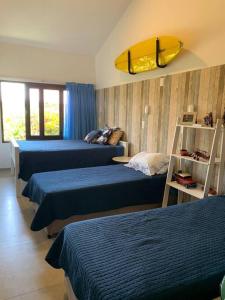 a bedroom with three beds and a surfboard on the wall at Casa de Praia Porto de Galinhas Toquinho in Ipojuca