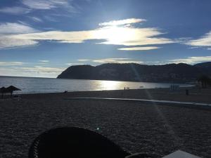 a beach with the sun shining on the water at HH Apartamento La Herradura Playa in La Herradura