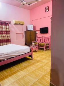 Habitación rosa con cama y TV. en Hotel New Star, en Multán