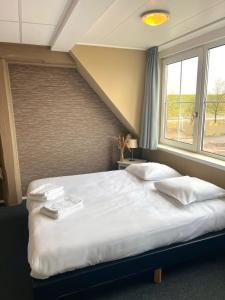 Un dormitorio con una gran cama blanca y una ventana en Bed and Breakfast De Zeehoeve, en Harlingen
