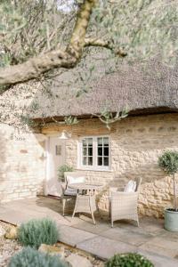 a stone house with chairs and a table in front of it at Greystone Guesthouse in Titchmarsh