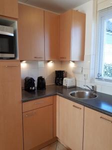 une cuisine avec un évier et un micro-ondes dans l'établissement Prachtige vakantiewoning-6P-afgesloten tuin-2 fietsen-dichtbij het strand, à Julianadorp