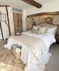 a bedroom with a large white bed with a stone wall at Greystone Guesthouse in Titchmarsh