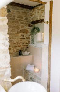 baño con pared de piedra y lavamanos en Greystone Guesthouse en Titchmarsh