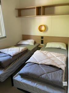 een kamer met drie bedden in een kamer bij Magnifique mobilhome-2 sdb-Camping 5 étoiles in Biscarrosse