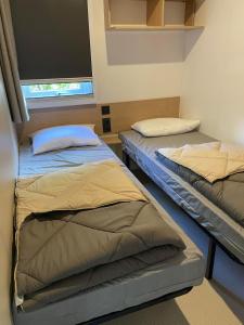 twee bedden in een kamer met een raam bij Magnifique mobilhome-2 sdb-Camping 5 étoiles in Biscarrosse