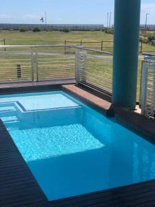 a blue swimming pool with a fence and a field at Quayside Waterfront Apartment in Durban