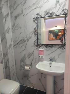 y baño con lavabo blanco y espejo. en Pinewood Guest House, en Iver