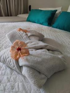 a towel on a bed with a flower on it at Pousada Waikiki Boutique in Pipa