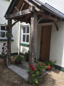 a wooden pergola in front of a house with flowers at Breathnach Cottage Annex Knockleagha Ballina F26 D7E2 in Ballina +17 photos