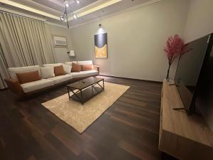 ein Wohnzimmer mit einem Sofa und einem Tisch in der Unterkunft تربل فور سويت - شقة في فيلا in Al Başar