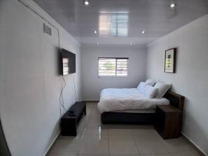 a white bedroom with a bed and a window at One bedroom apartment. in Cape Town