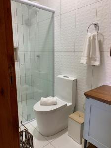 a bathroom with a toilet and a glass shower at Pousada Perola da Praia in Penha