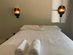 a white bed with two rolled towels on it at Pousada Maikai Garden in Porto Belo