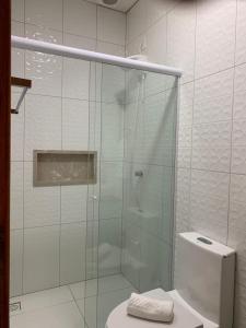 a glass shower in a bathroom with a toilet at Pousada Perola da Praia in Penha