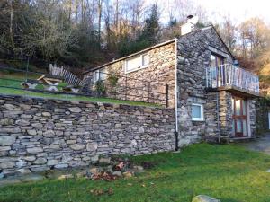 een stenen huis met een stenen muur en een balkon bij Romantic getaway, little two bed, two bath barn conversion with amazing views and parking in Ambleside