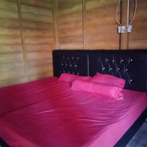 BihaにあるKarang Besi Losmenのピンクのベッド(黒いヘッドボード、ピンクの枕付)