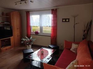 sala de estar con sofá rojo y mesa de cristal en Ferienhaus ANNE, en Thale