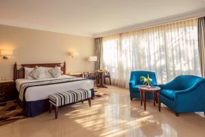 a hotel room with a bed and two blue chairs at Stella Di Mare Grand Hotel in Ain Sokhna +45 photos