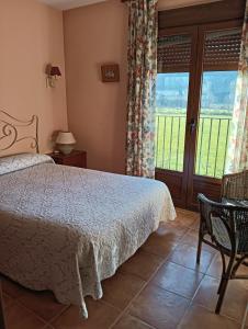 a bedroom with a bed and a table and a window at Hostal Sol de la Vega in Albarracín