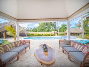 a patio with couches and a table and a pool at Sun Soul - Caribbean 9br Villa In Sosua in Sosúa
