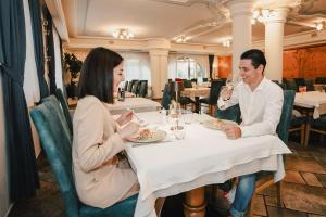 a man and woman sitting at a table in a restaurant at Hotel Bellavista in Cavalese