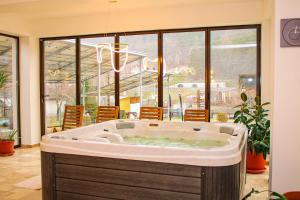 a large jacuzzi tub in a room with windows at Pensiunea Tobo in Baia de Fier