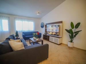 een woonkamer met een blauwe bank en een tv bij 7br Massive Villa In Sosua - 2mins From Nightlife in Sosúa