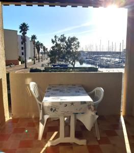 uma mesa e cadeiras numa varanda com vista para um porto em Le Lamparo entre Port et Mer em Port Leucate