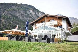 a building with chairs and umbrellas in front of it at Restaurant & Hostel Hole in One in Randa