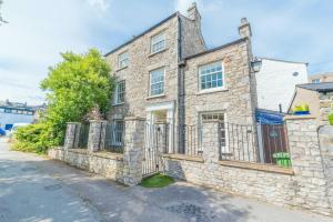 uma casa de pedra com um portão e uma cerca em Central Kendal Georgian Home with private courtyard & free parking em Kendal